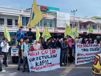 Mahasiswa PMII Bengkalis membentangkan spanduk tuntutan dalam aksi demo di depan Kantor Bupati Bengkalis.