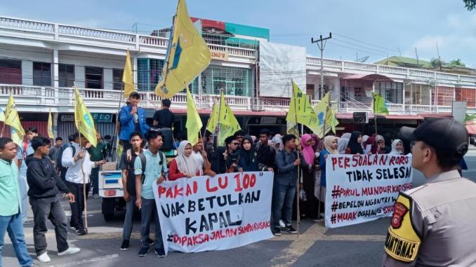 Mahasiswa PMII Bengkalis membentangkan spanduk tuntutan dalam aksi demo di depan Kantor Bupati Bengkalis.