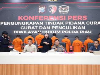 Pejabat Polda Riau memaparkan pengungkapan kasus pencurian, perampokan, dan penculikan dalam konferensi pers bersama Tim RAGA di Mapolda Riau, dengan sejumlah tersangka berdiri di belakang mengenakan baju tahanan oranye.