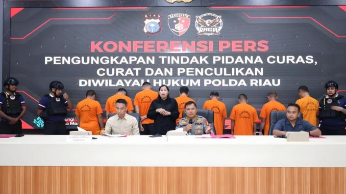 Img_25-10-15_12-30-37-146 Pejabat Polda Riau memaparkan pengungkapan kasus pencurian, perampokan, dan penculikan dalam konferensi pers bersama Tim RAGA di Mapolda Riau, dengan sejumlah tersangka berdiri di belakang mengenakan baju tahanan oranye.