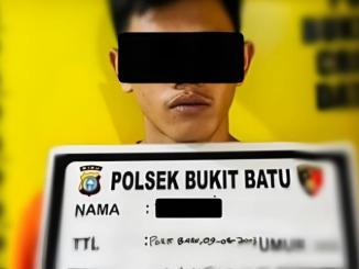 tersangka sabu berdiri di depan papan identifikasi Polsek Bukit Batu