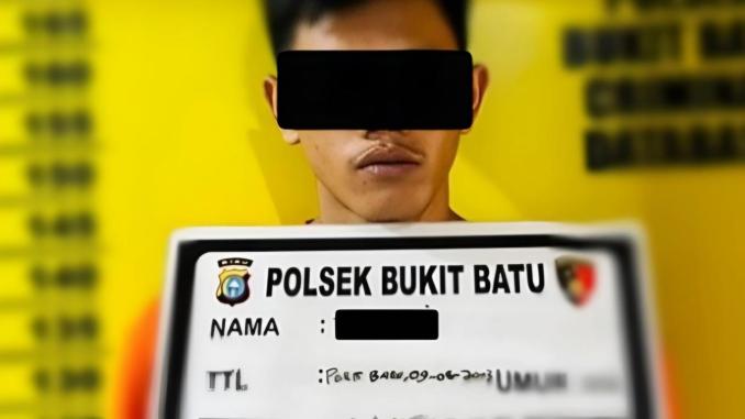 tersangka sabu berdiri di depan papan identifikasi Polsek Bukit Batu
